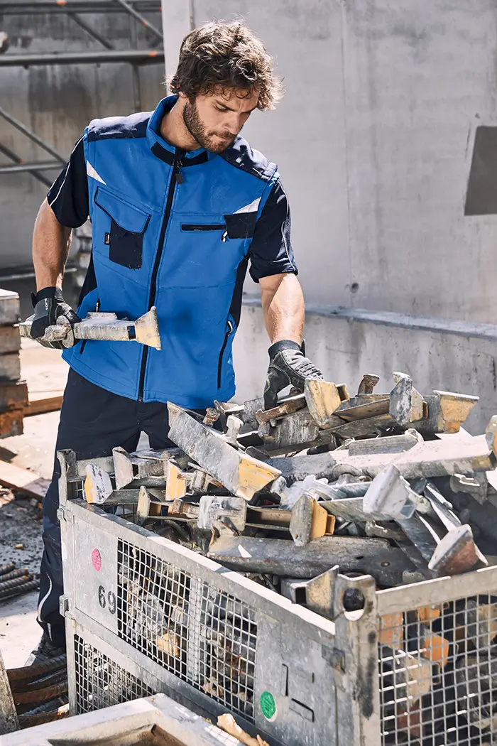 Handwerker, Bauarbeiter in Aktion auf der Baustelle mit , mit Daiber Softshell Arbeitsweste JN845, Farbe royal-navy