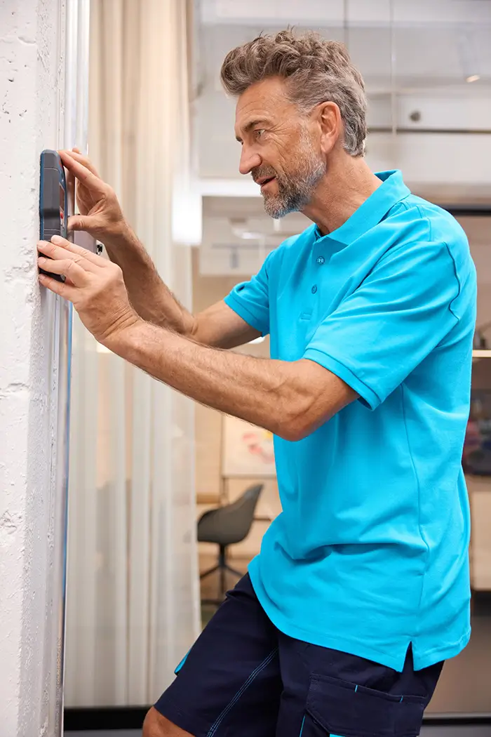Seitenansicht des Herren Workwear Poloshirt JN1806 in türkis, Handwerker in Bewegung bei der Arbeit