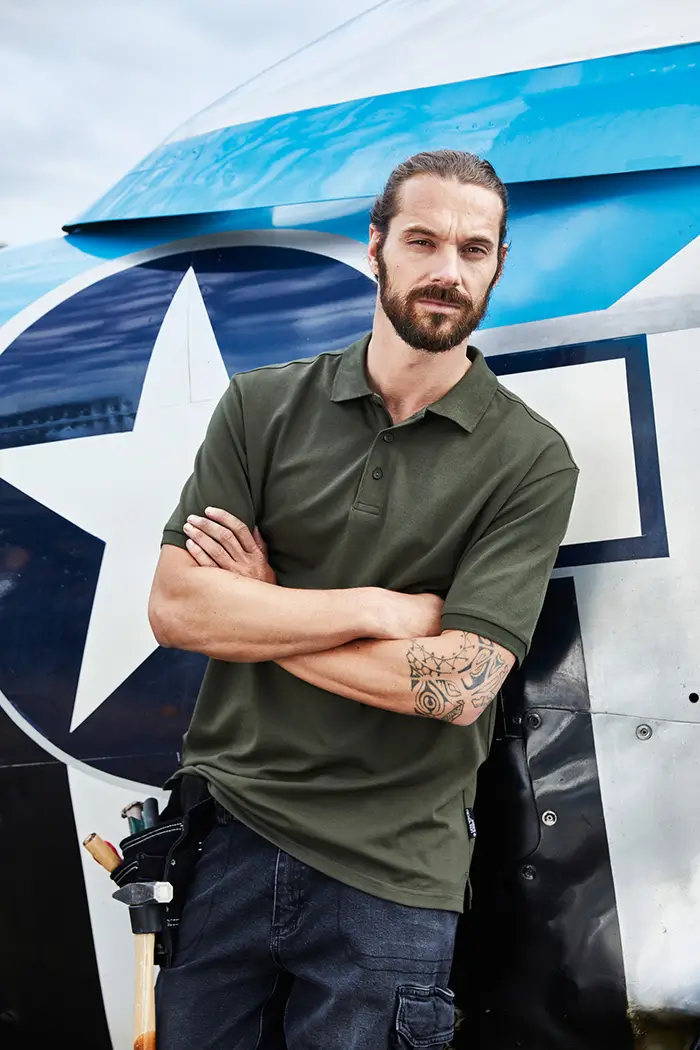 Herren Workwear Poloshirt JN1806 in olivgrün, frontal getragen von Handwerker bei der Arbeit