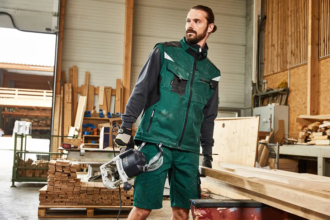 Schreiner in der Werkstatt mit Softshell Arbeitsweste dunkelgrün-schwarz, Daiber JN845