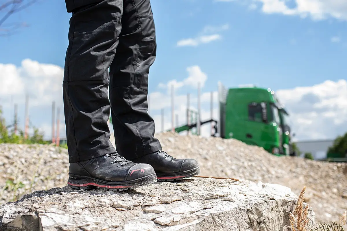 HAIX Trekker Pro 2.0 S3 Mid Sicherheitsschuh in Schwarz-Rot im Baustelleneinsatz auf einem großen Stein
