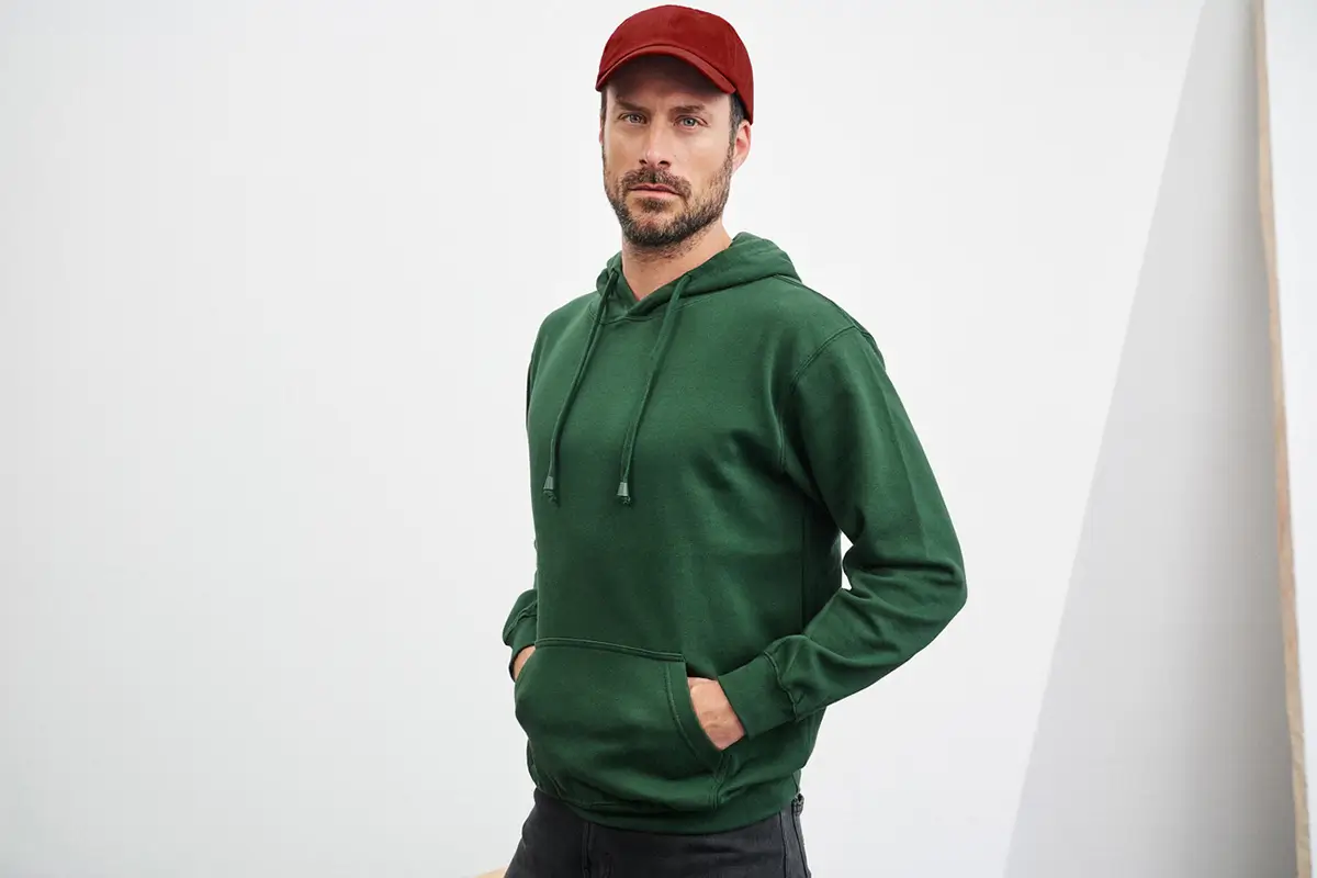Mann in Pose mit Daiber Kapuzensweatshirt, dunkelgrün – ideal für komfortable Freizeitoutfits und urbanen Stil