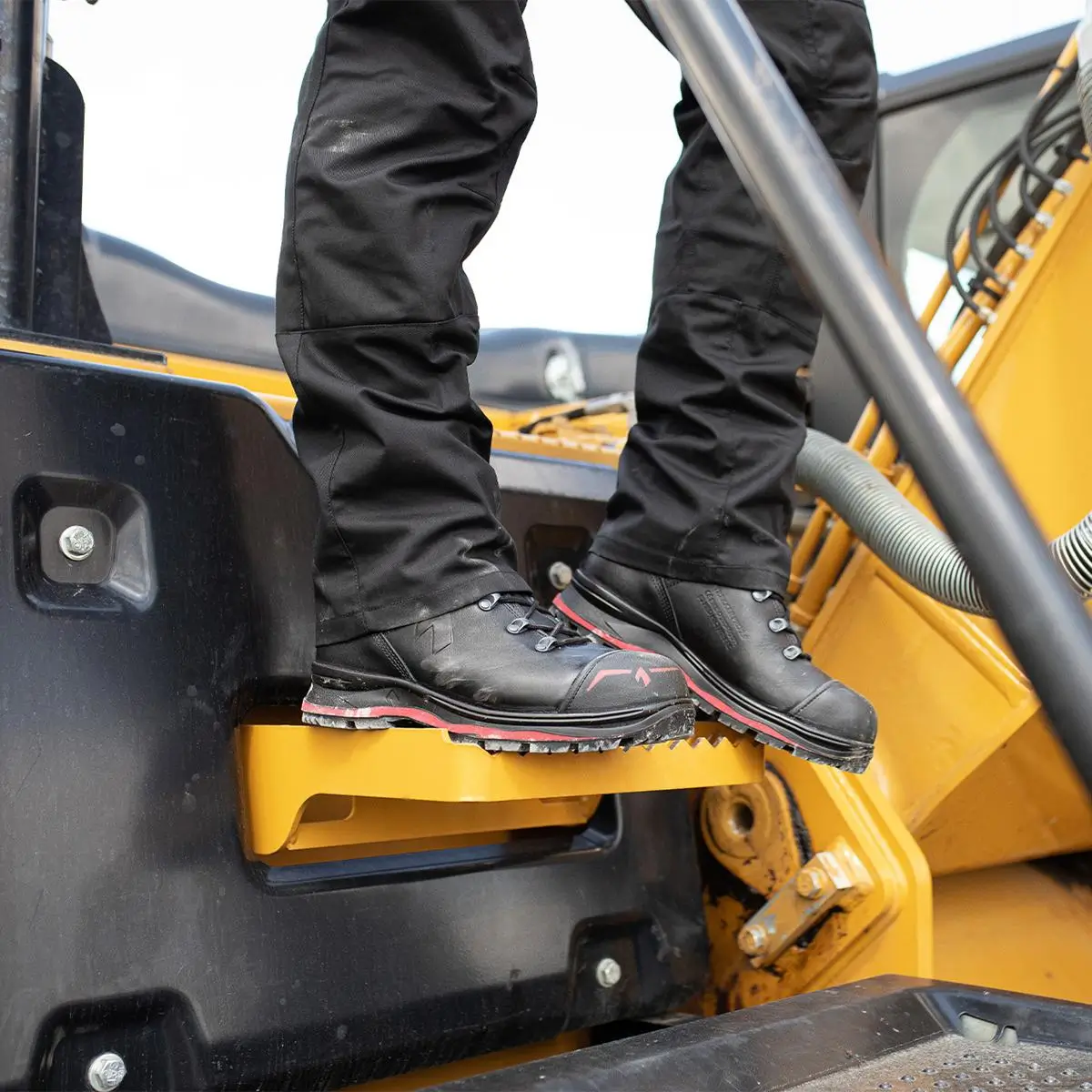 HAIX Trekker Pro 2.0 S3 Mid Sicherheitsschuh in Schwarz-Rot auf einem Baustellenbagger
